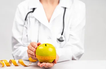 Female medical doctor holding an apple with measure tape