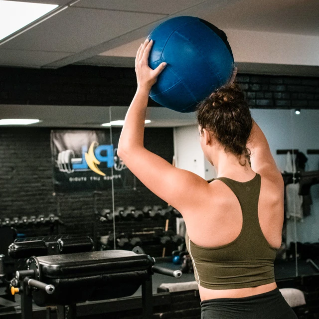 Girl exercising with a blue training ball at Power lift studio in Boston